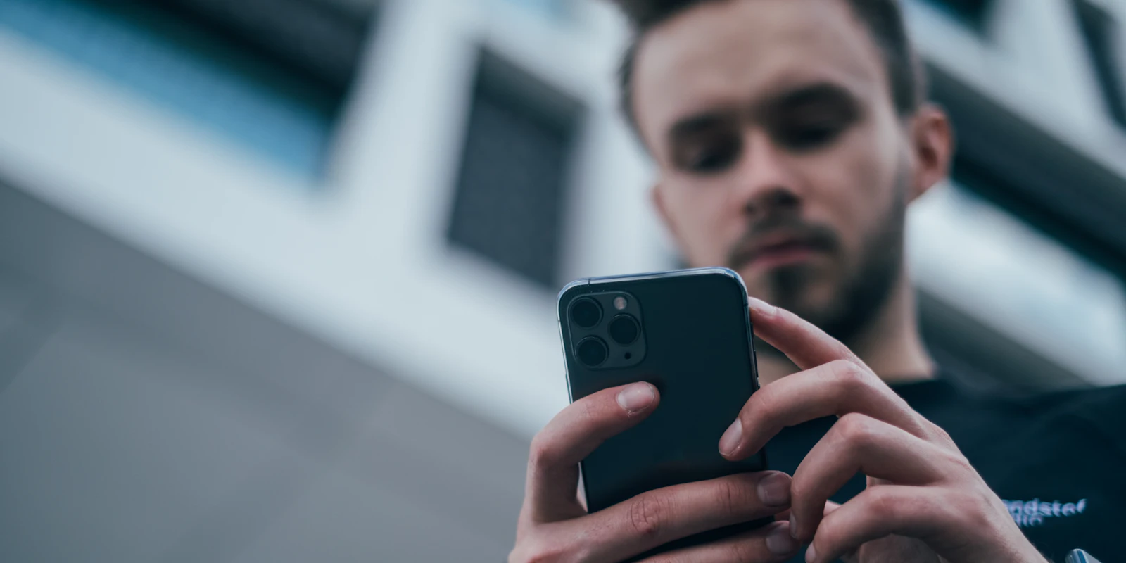 Muž soustředěně používá aplikaci v telefonu.